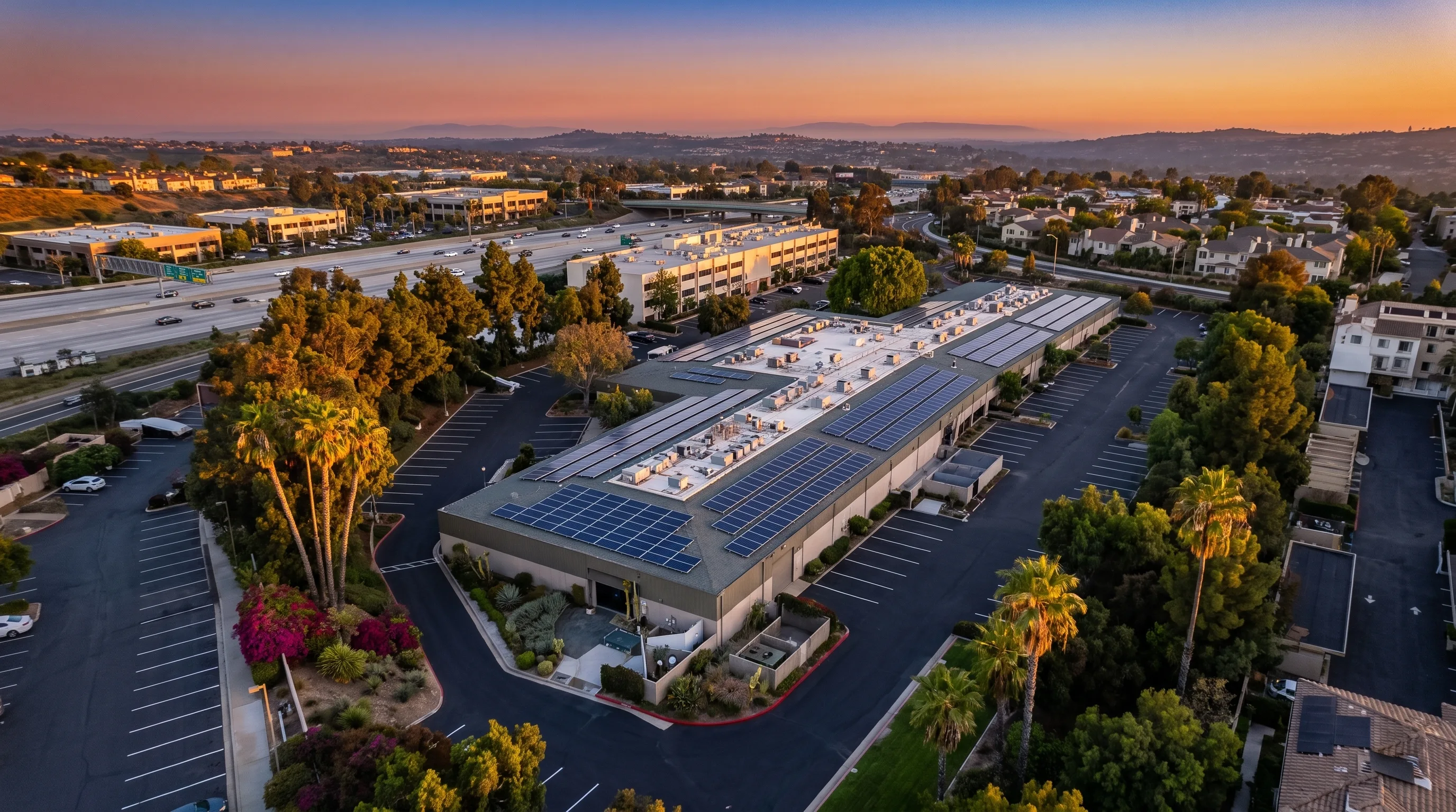 Aerial view of a commercial flex building with a large rooftop solar array at golden hour